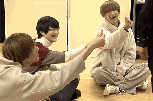 a group of young men sitting on the floor laughing