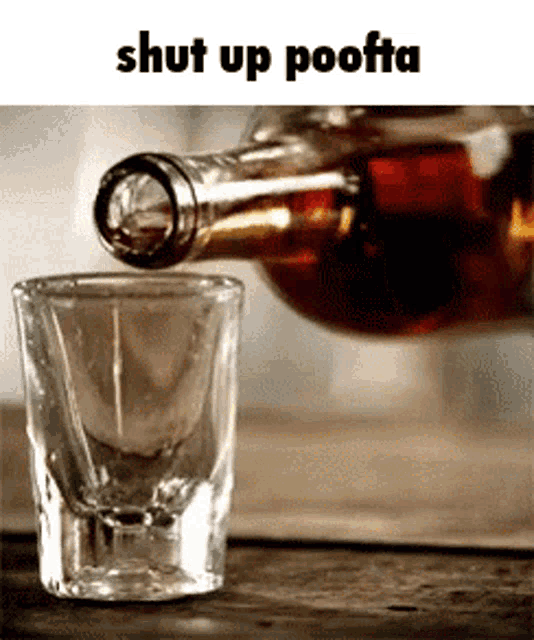 a bottle of alcohol is being poured into a shot glass on a wooden table .