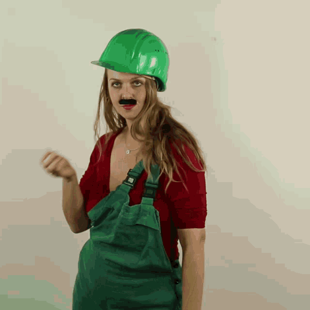 a woman wearing overalls and a hard hat has a fake mustache on her face