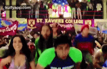 a group of people are dancing in a room with a banner that says st. xavier 's college on it .