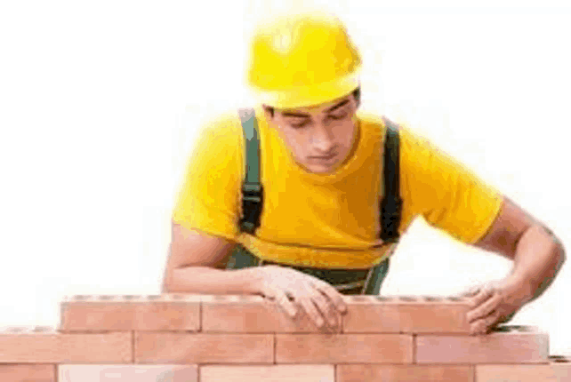 a construction worker is laying bricks on a wall .