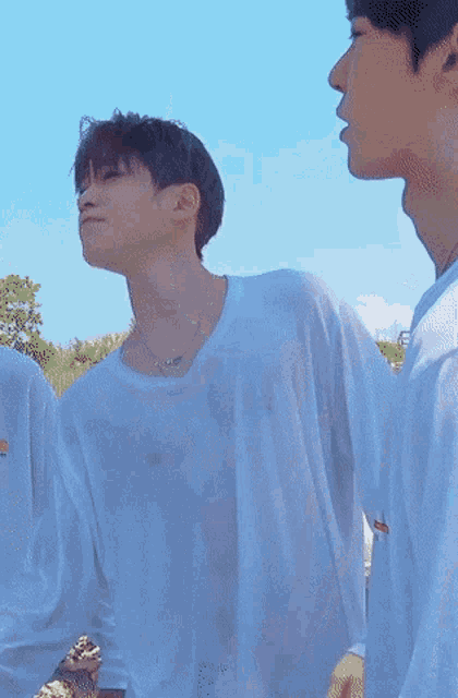 a man in a white shirt with a necklace around his neck looks up at the sky