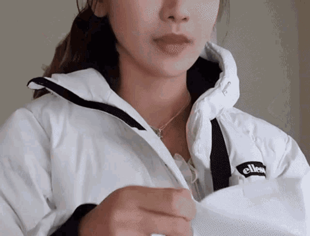 a woman wearing a white jacket with the word ellesse on the front