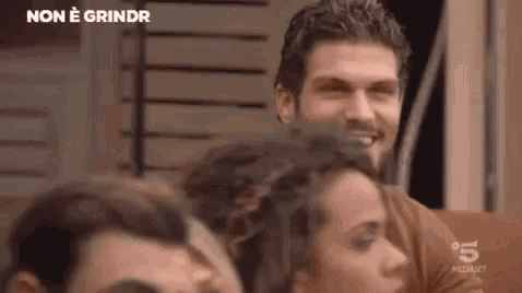 a group of people are sitting in a room and a man is smiling at the camera .