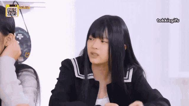 a girl with long black hair is sitting in front of a sign that says new tips .