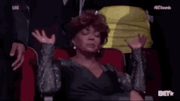 a woman is sitting in a theatre watching a show with bet awards written on the bottom of the screen