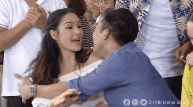 a man in a blue shirt is hugging a woman in a crowd of people ..