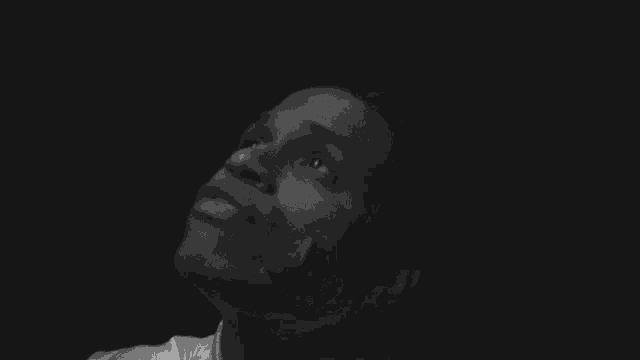a black and white photo of a young man looking up at the sky