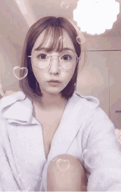 a woman wearing glasses and a white robe is sitting down
