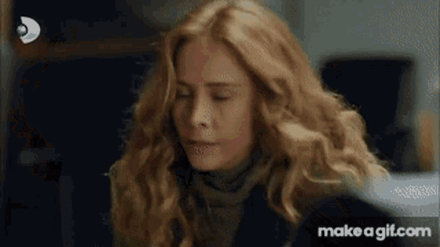 a woman with blonde hair is sitting down with her eyes closed and a scarf around her neck .