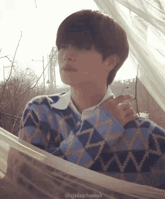 a man wearing a blue and white sweater is looking out of a window