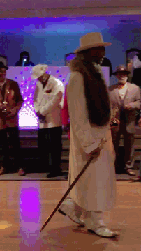 a man with a cane is standing on a stage with other people