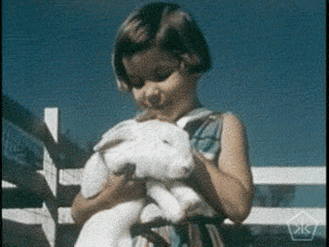 a little girl is holding a small white rabbit in her hands