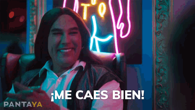 a man in a wig is sitting in front of a neon sign that says pantaya
