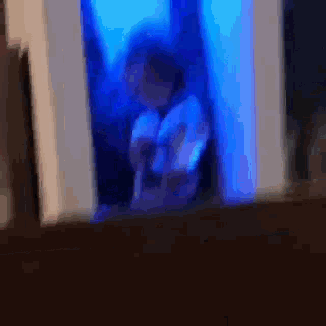 a blurry picture of a person sitting in a dark room with blue lights behind them