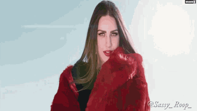 a woman wearing a red fur coat with the name sassy_roop_ on the bottom