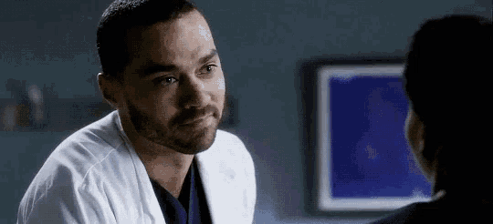 a man in a white lab coat is talking to a woman in a hospital room .