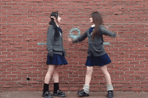 two girls standing in front of a brick wall