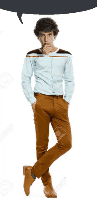 a man in a blue shirt and brown pants stands with his hands in his pockets