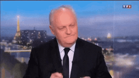 a man in a suit and tie is giving a speech on a television screen .