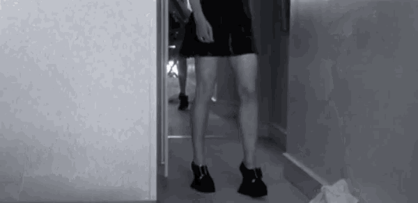 a black and white photo of a woman 's legs standing in a hallway