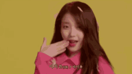 a woman in a pink shirt is holding her hair in the air .