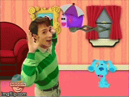 a boy in a green and green striped shirt is holding a purple house in a room