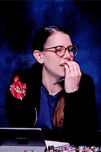 a woman wearing glasses is sitting at a desk with a pen in her hand