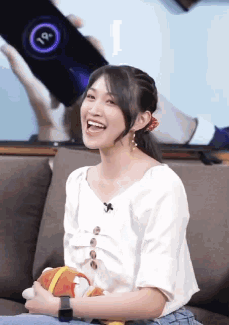 a woman is sitting on a couch with a phone that says 19 degrees on it