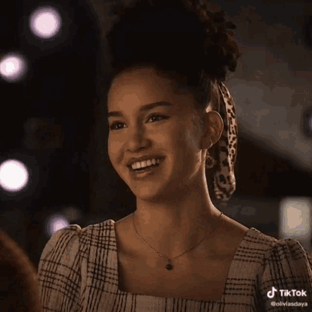 a woman wearing a plaid dress and a leopard print scarf is smiling ..