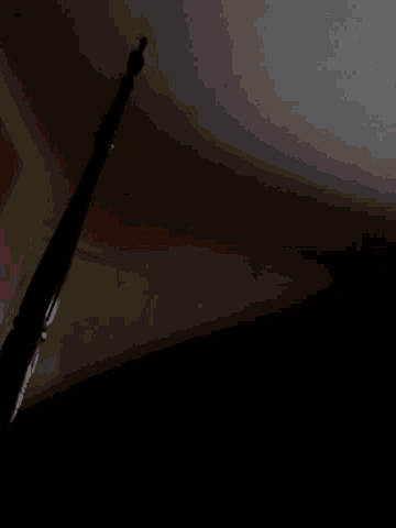 a dark corner of a room with a white wall and a wooden railing
