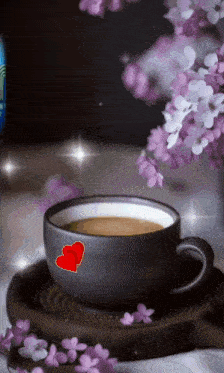a cup of coffee with two hearts on it and purple flowers in the background