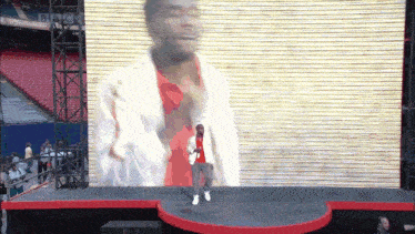 a man is dancing on a stage in front of a large screen with bbc written on it