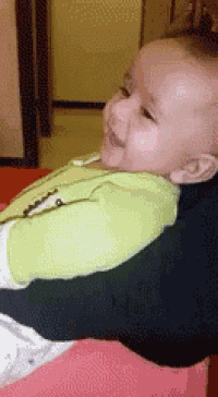 a baby wearing a green shirt is being held by someone
