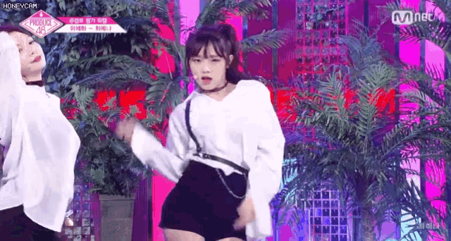 a girl is dancing on a stage in front of a palm tree .
