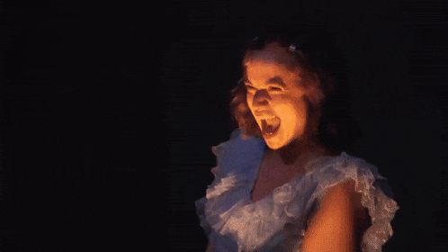 a woman in a white dress is screaming with her mouth open