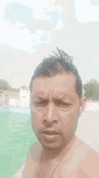 a man without a shirt is taking a picture of himself in a pool .