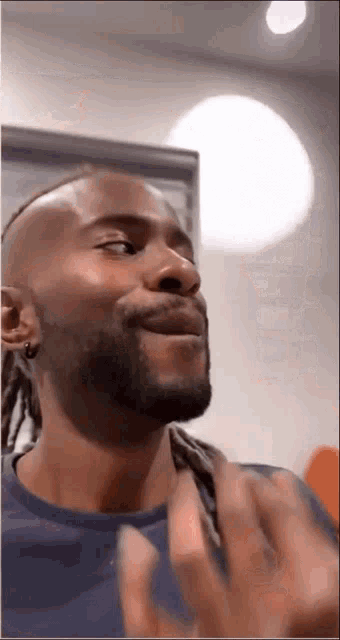 a man with dreadlocks and a beard is smiling and waving his hands