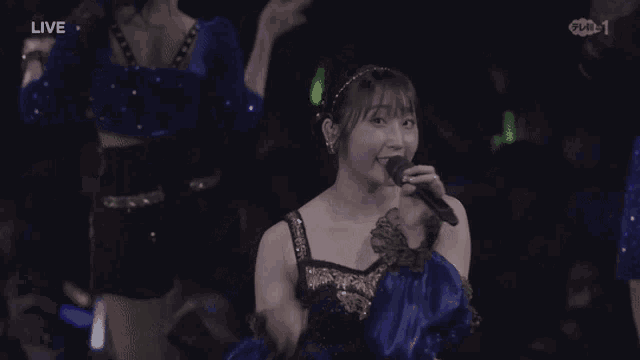 a woman singing into a microphone with the word live in the corner