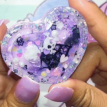 a person with purple nails holds a heart shaped object