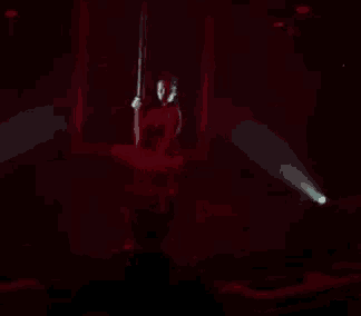 a woman is dancing on a pole in a dark room
