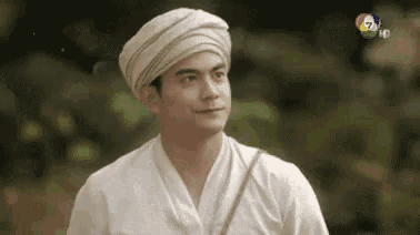 a man wearing a turban and a white shirt is standing in a field .