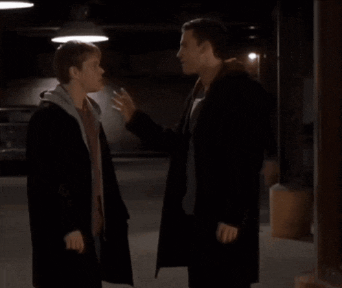 two men standing next to each other in a parking garage