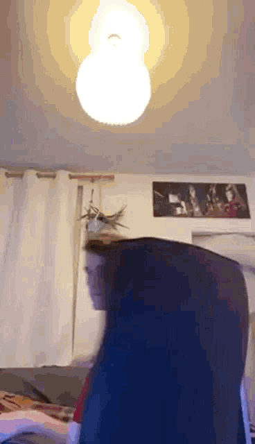 a person is sitting in a chair in a living room with a light on the ceiling .