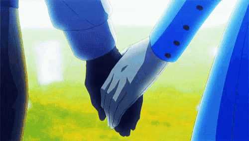 a man and a woman are holding hands in a field of grass .