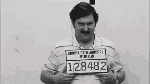 a man with a mustache is holding a sign that says ' otto judicial medellin ' on it .