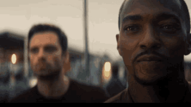 a man with a beard is standing next to another man in a blurry photo