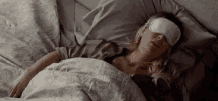 a woman is sleeping in bed wearing a sleep mask .