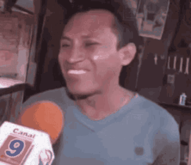 a man in a blue shirt is talking into a microphone with the number 9 on it .