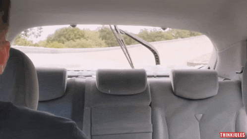 a man sitting in the back seat of a car with thinki jules written on the bottom right corner